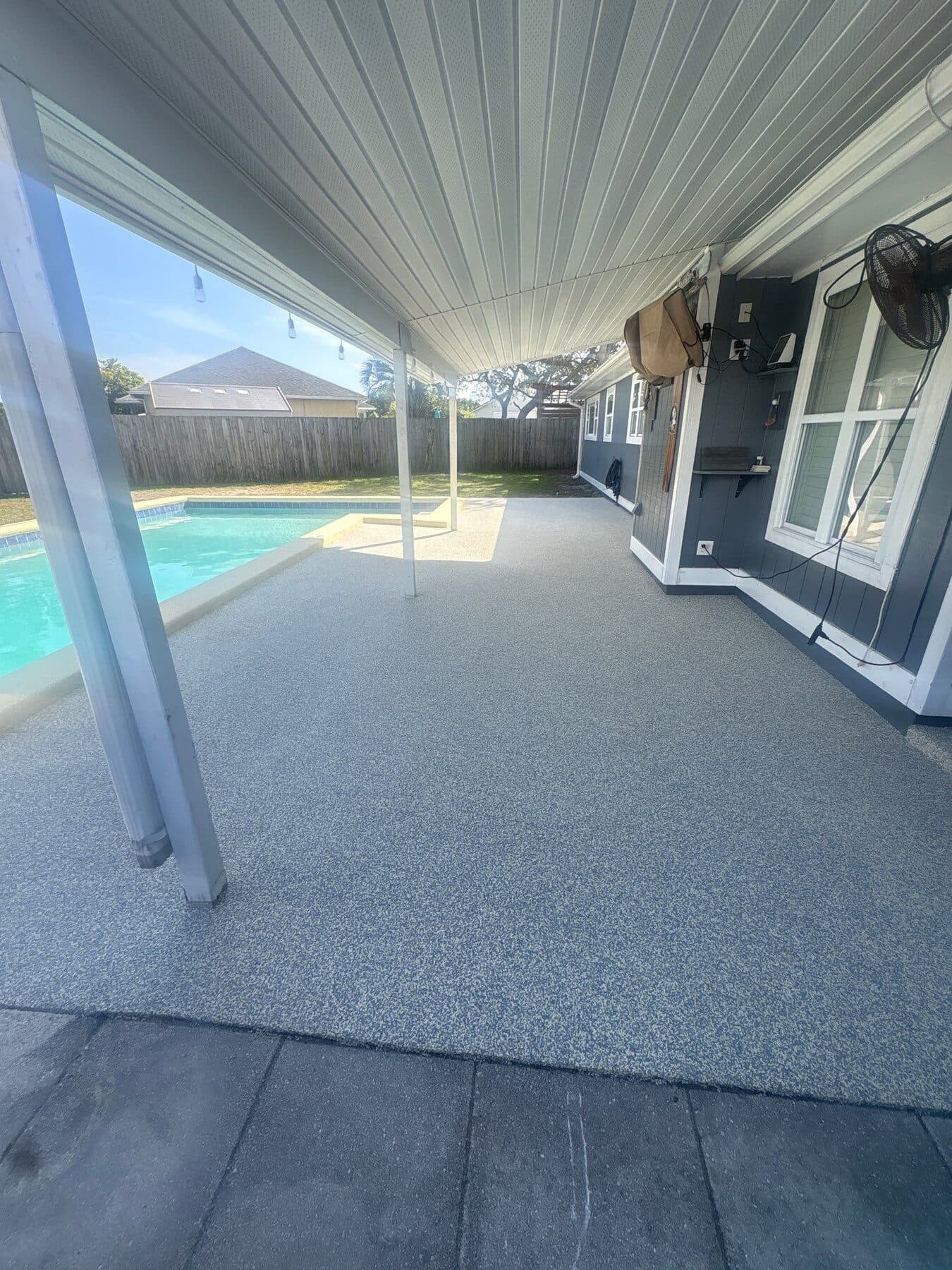 Finished cool neutral pool deck beneath a covered backyard patio