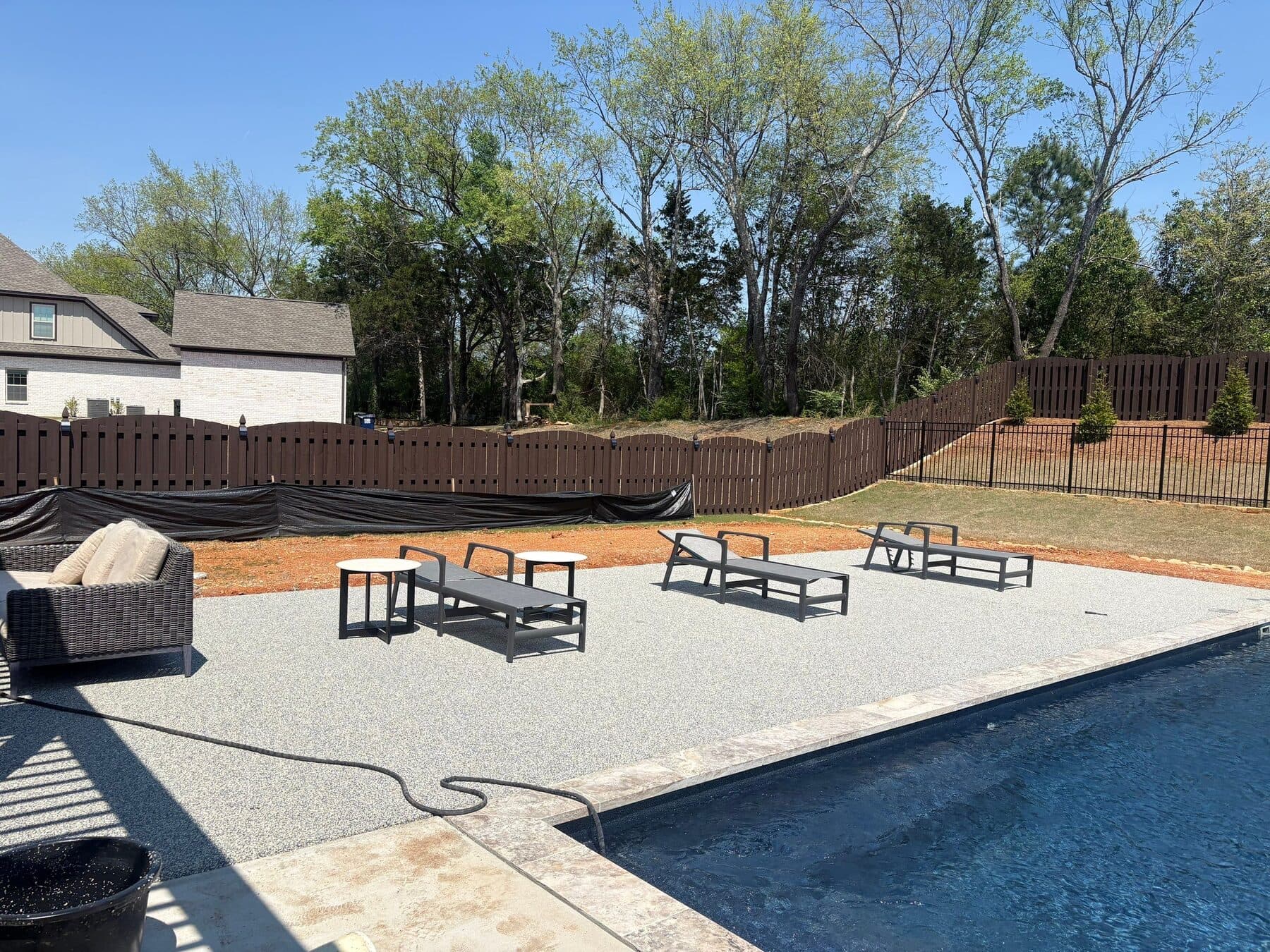 Finished light neutral pool deck with backyard lounge seating