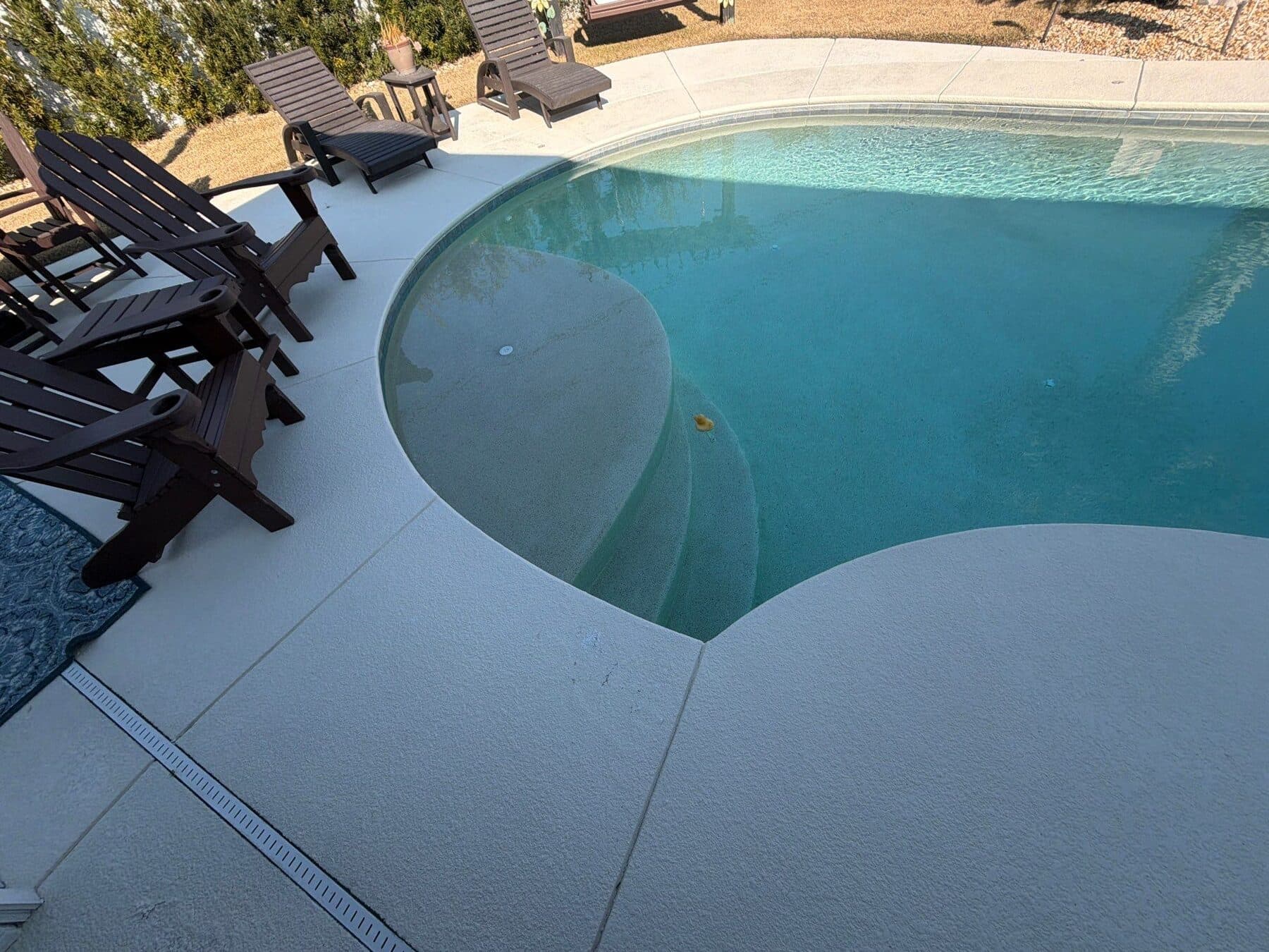 Finished light neutral surface around a curved residential pool