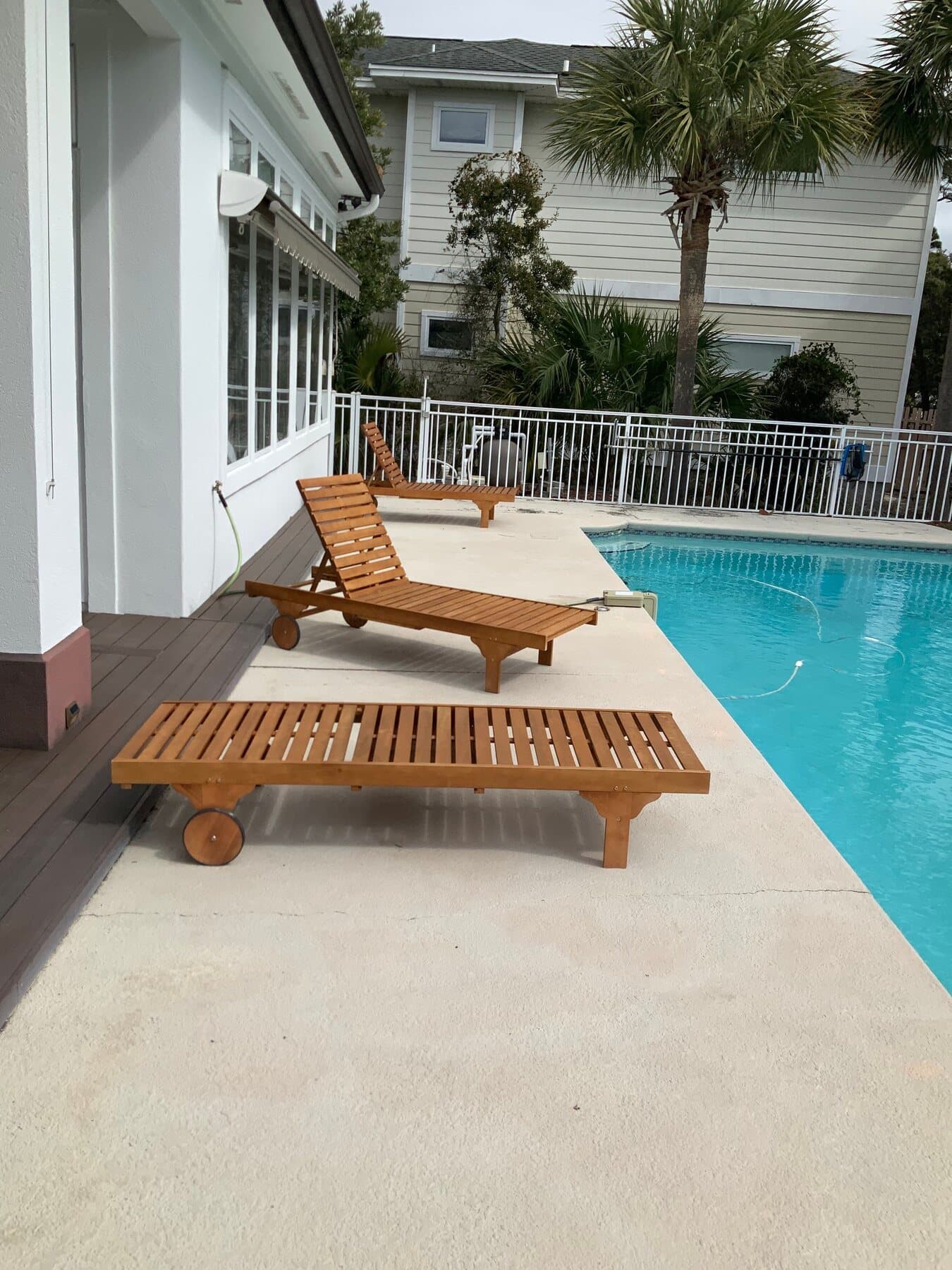 Finished light pool deck with lounge seating and palm trees