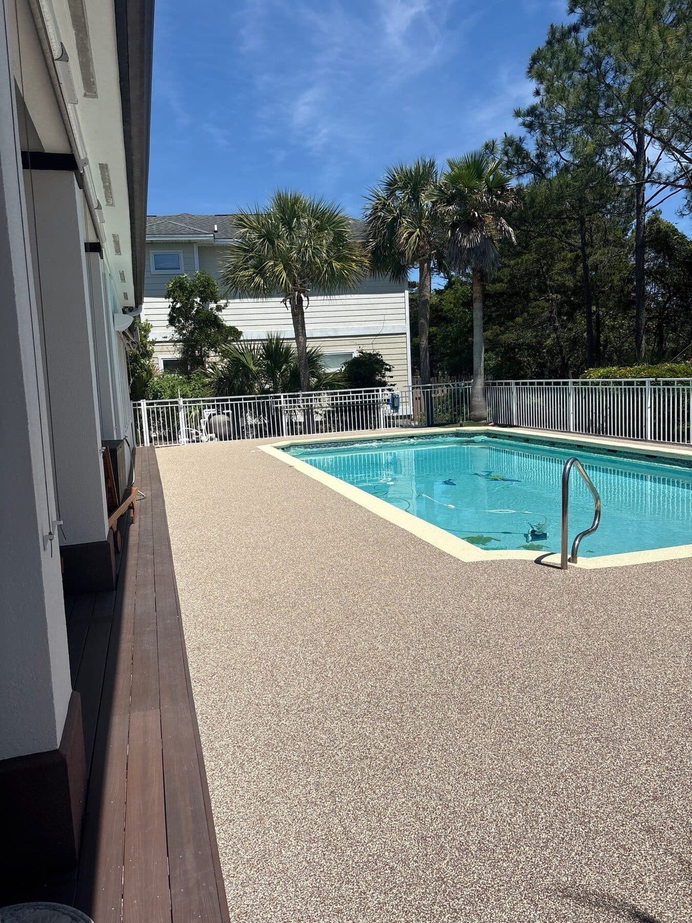 Finished light neutral pool deck with tropical landscaping