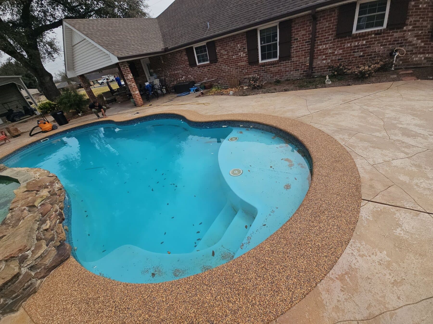 Finished brown Sandstone pool deck around a curved backyard pool