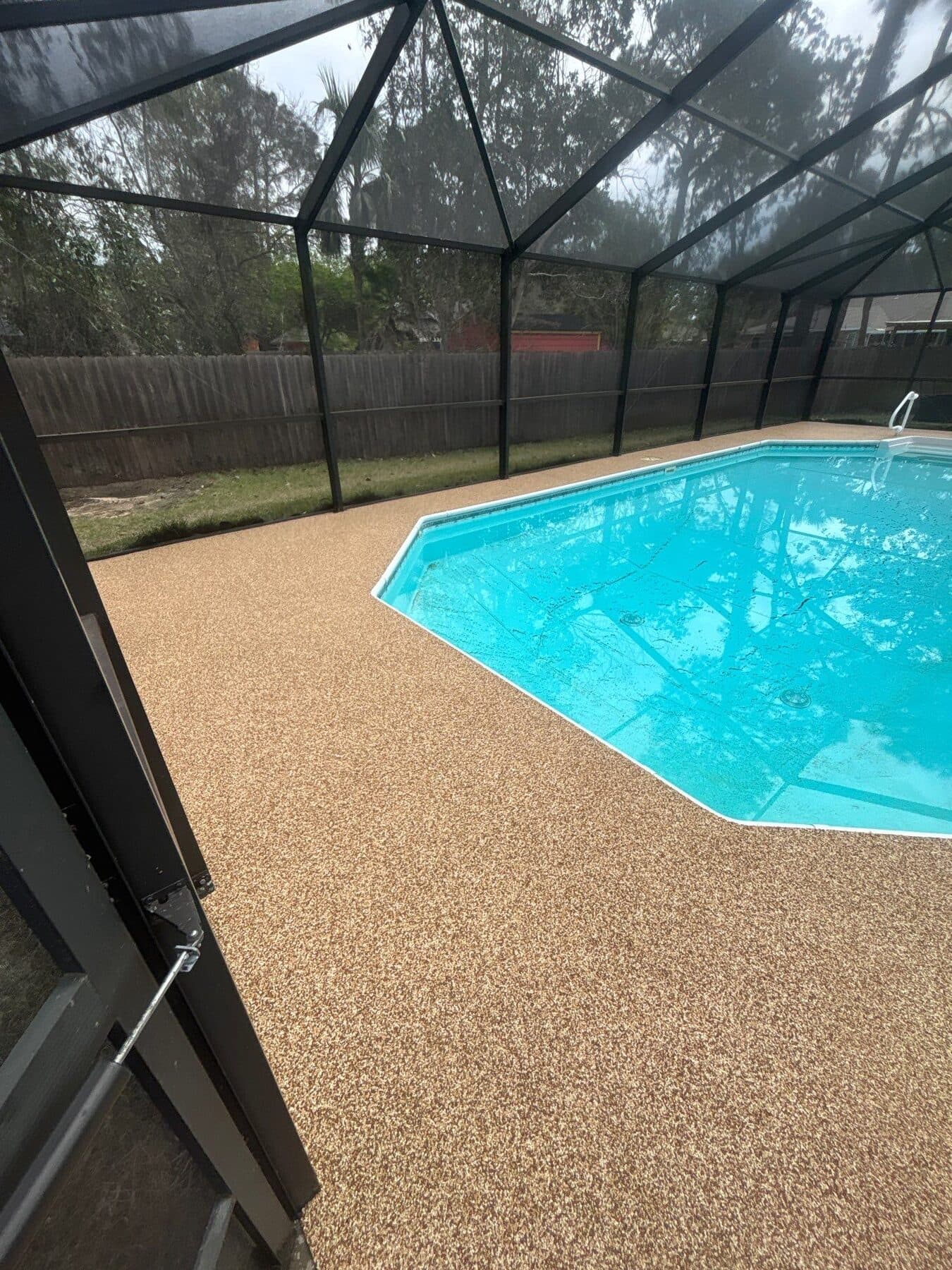 Finished warm neutral pool deck inside a screened enclosure
