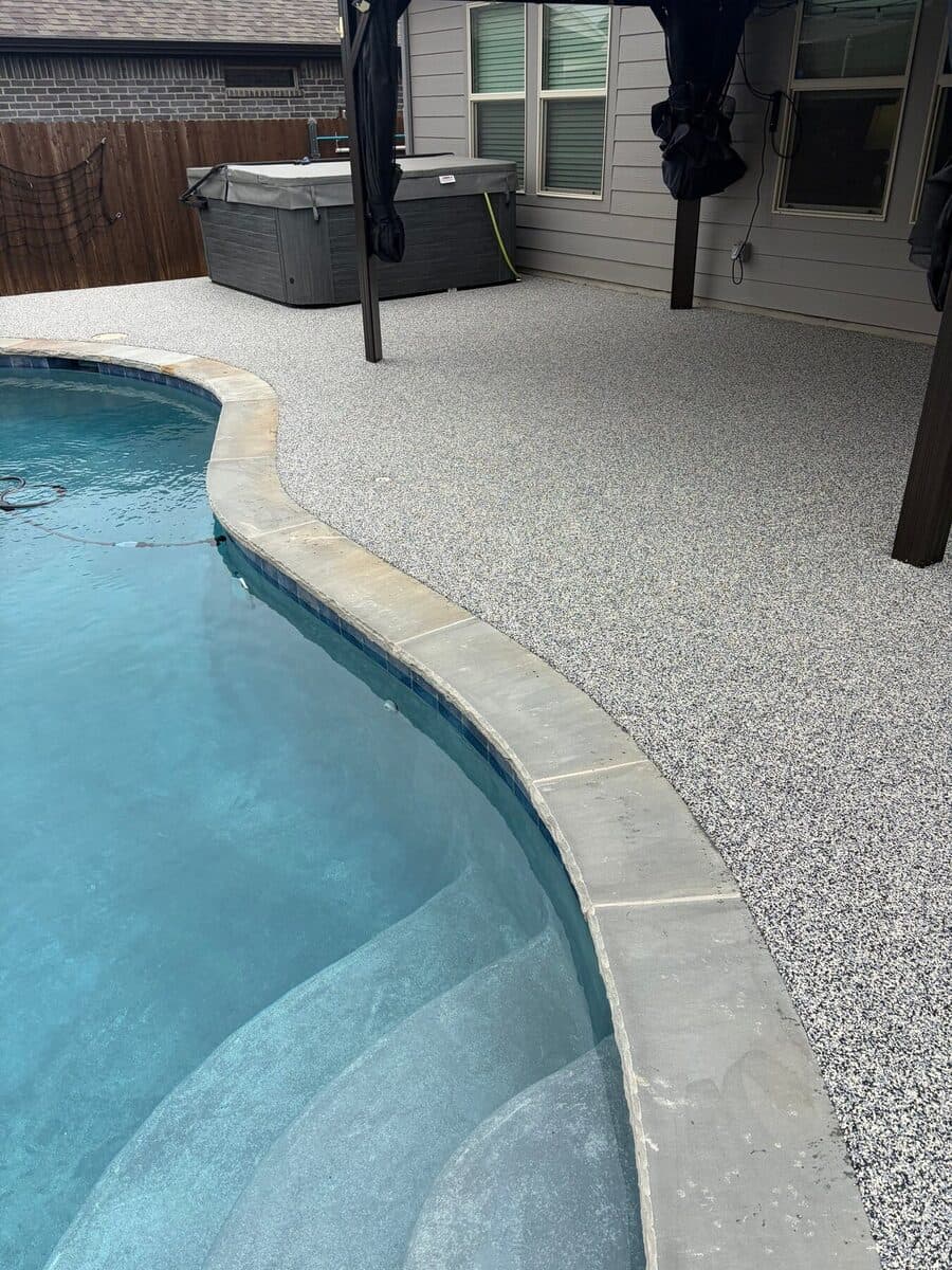 Finished curved Nickel pool deck beside a shaded cabana